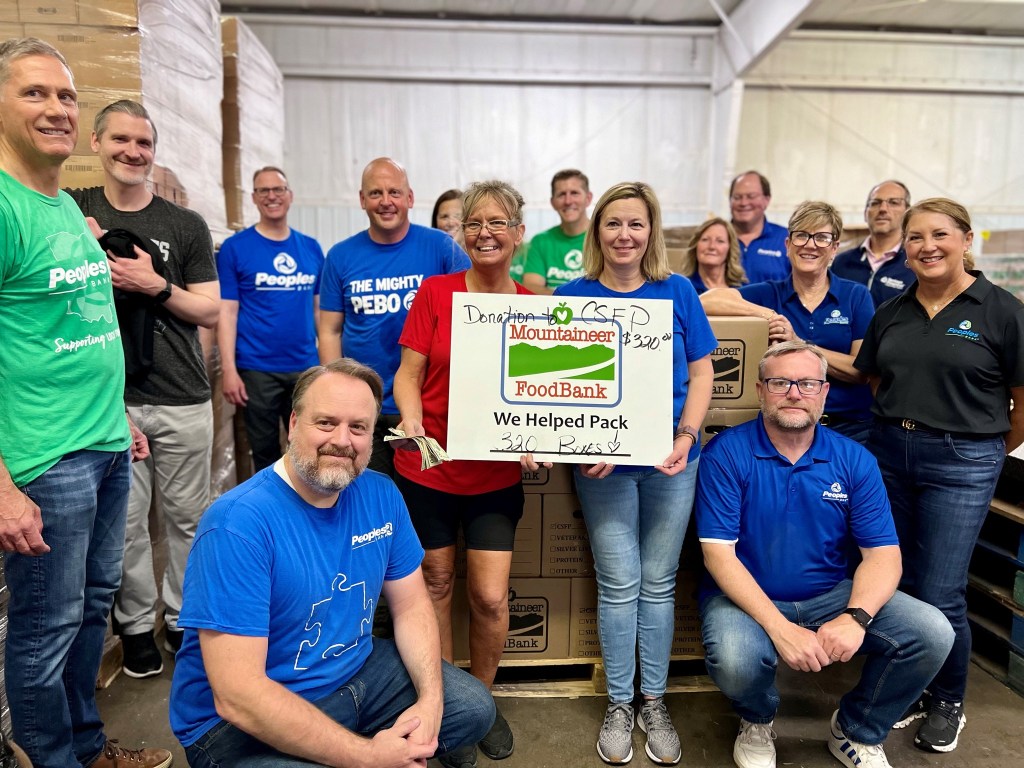 Peoples Bank employees stand in front of 320 food boxes they packed for Mountaineer Foodbank.