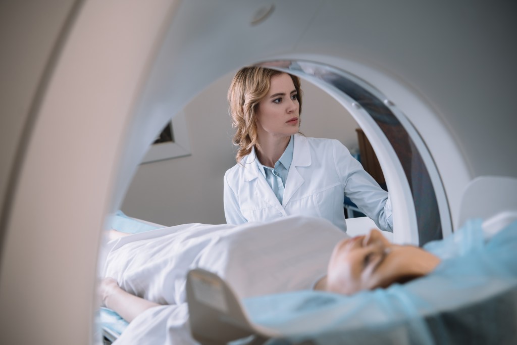 A female medical technician assists a patient for a CAT scan.