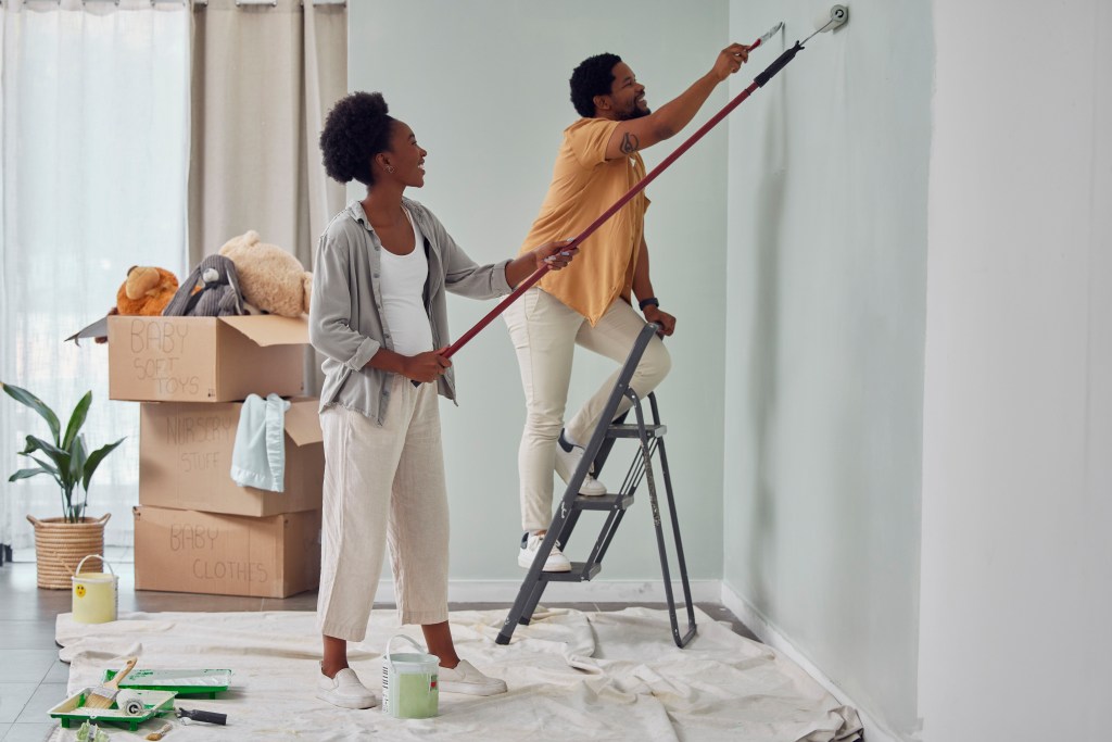 A young couple paints the walls of a house they just moved into.
