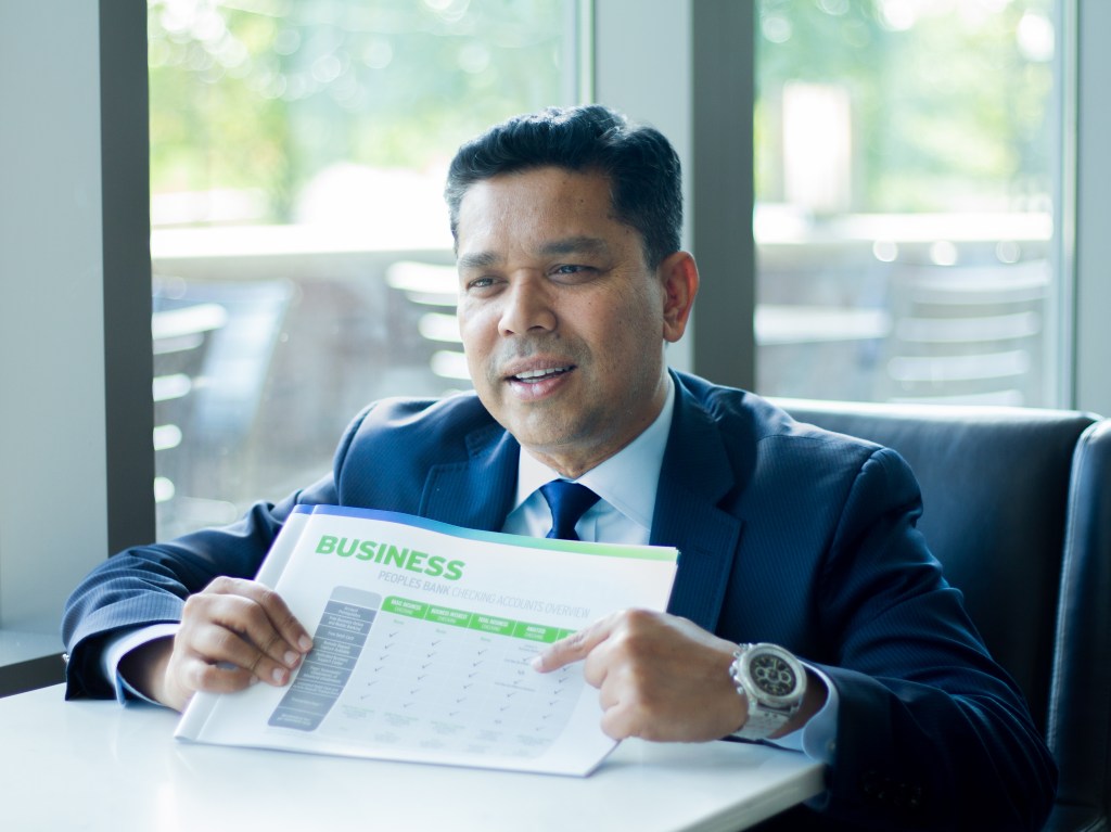 A Peoples Bank business banker shows a customer a pamphlet with business account options.