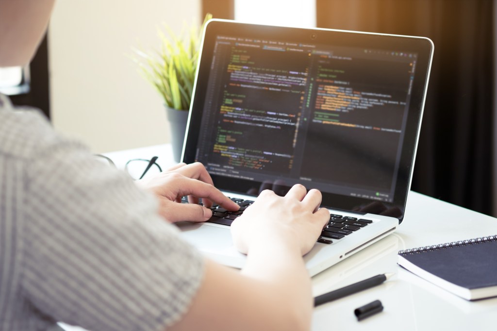 A person reviews developer code while working on their laptop.