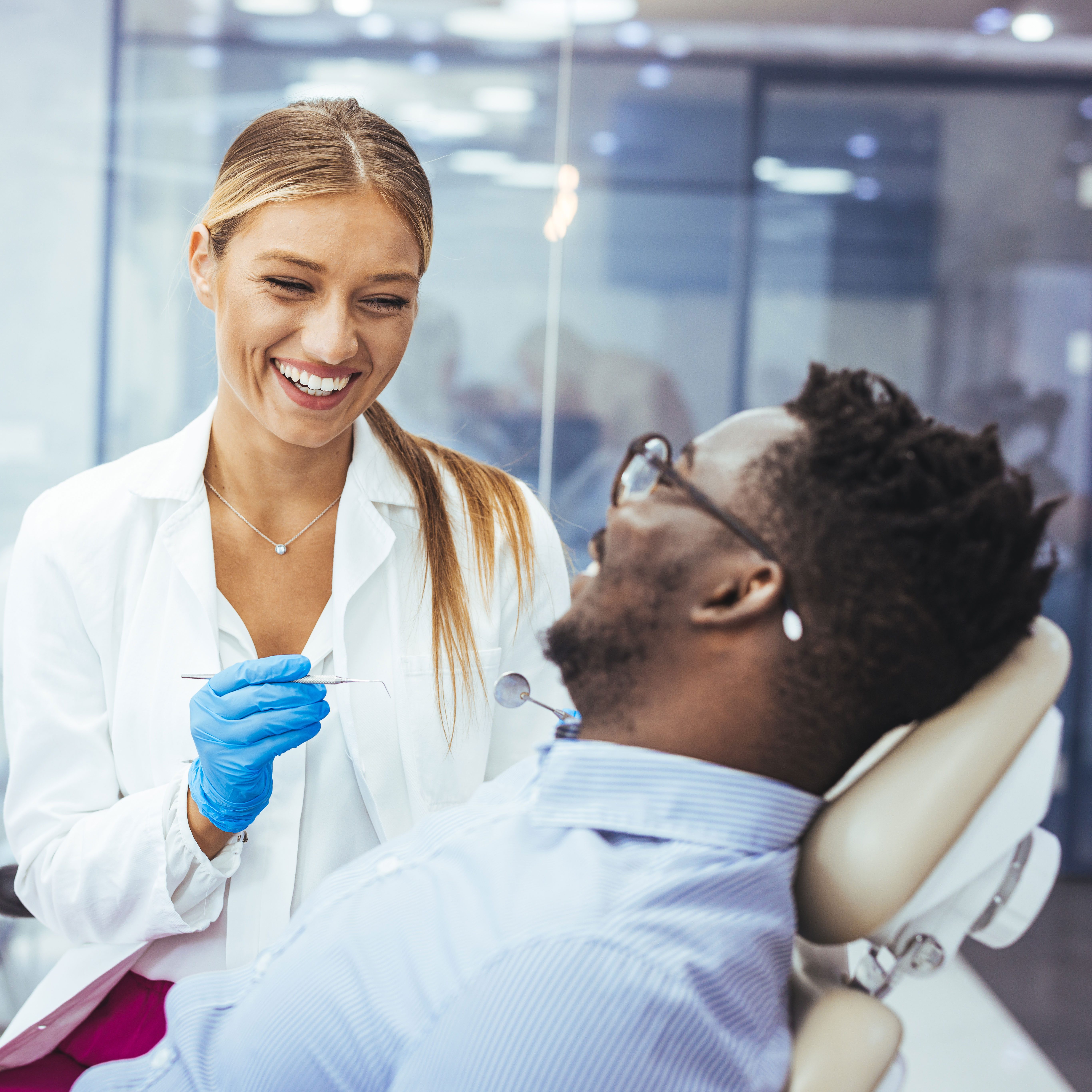 Young man patient having dental treatment at dentist's office. Female dentist working on patient's teeth.