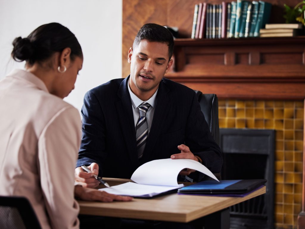 A lawyer consults a client in his office with legal paperwork.