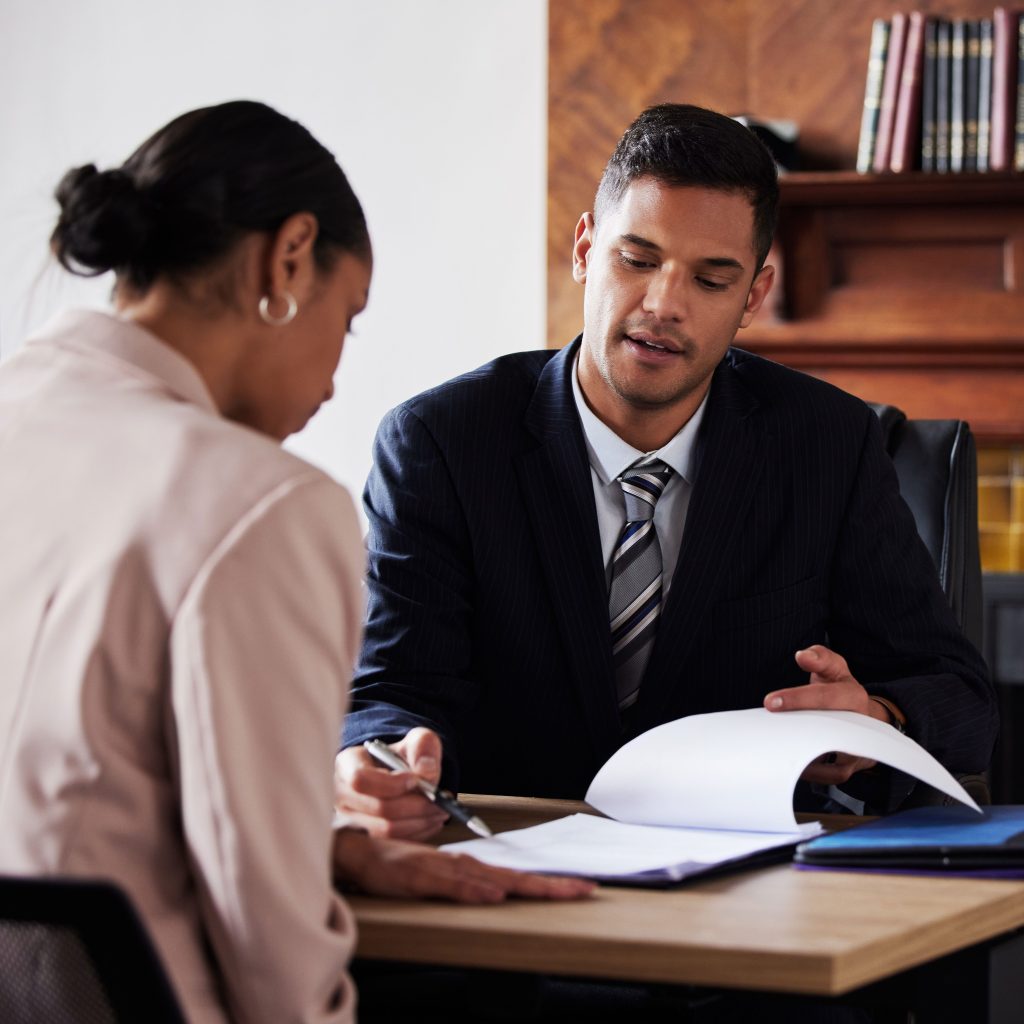 A lawyer consults a client in his office with legal paperwork.