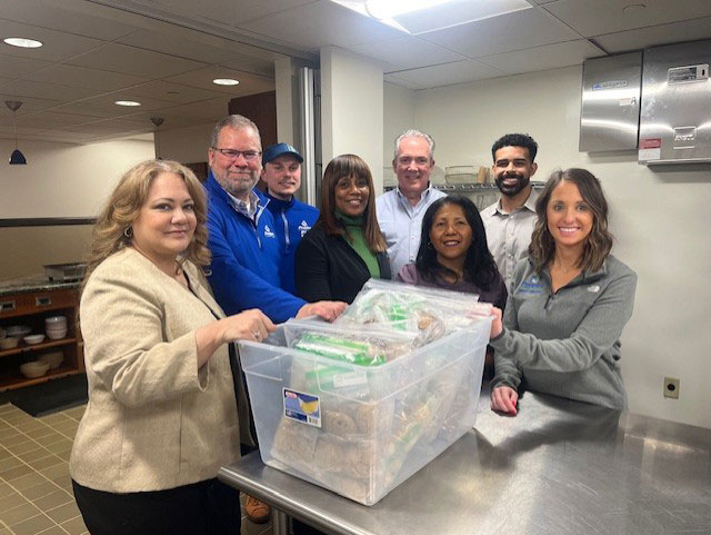 Peoples Bank associates stand in the Ronald McDonald House kitchen with supplies to bake cookies.
