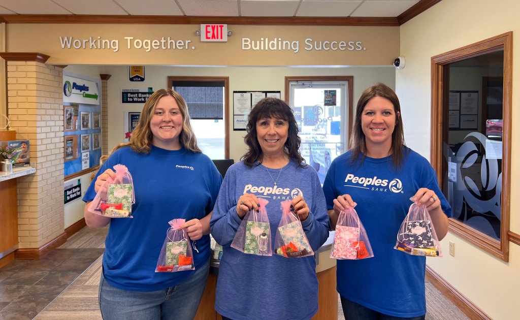 Three Peoples Bank associates pose with handmade treat bags for Mother's Day celebrations.