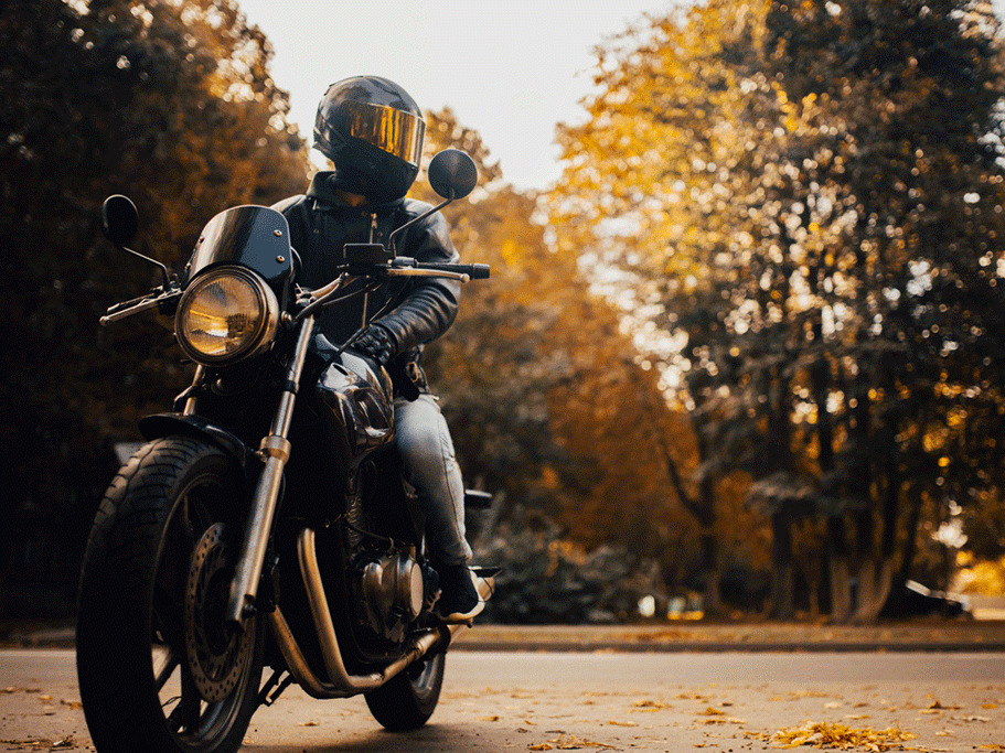 Motorcyclist in a helmet sitting on classic motorcycle in the fall.