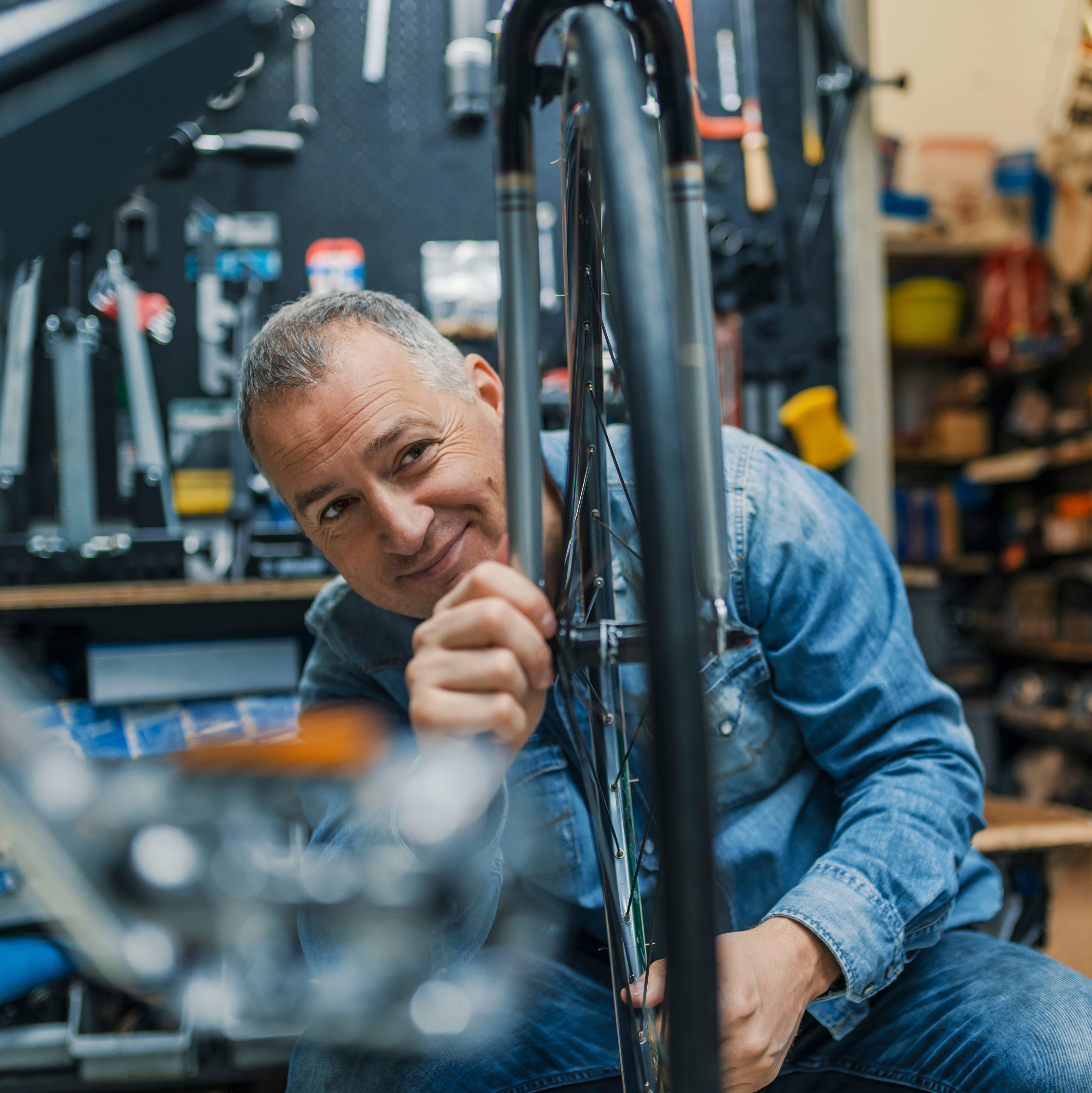 Bicycle mechanic replaces the wheel of a bicycle in the middle of a shop.