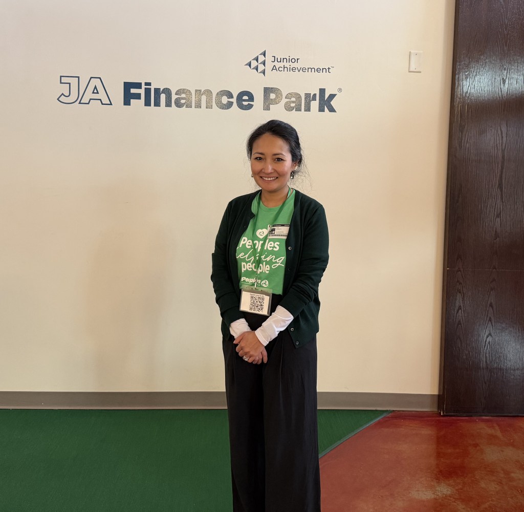 Peoples Bank Associate Ayia Cernica stands in front of the Junior Achievement Finance Park building in Fairfax, Virginia.