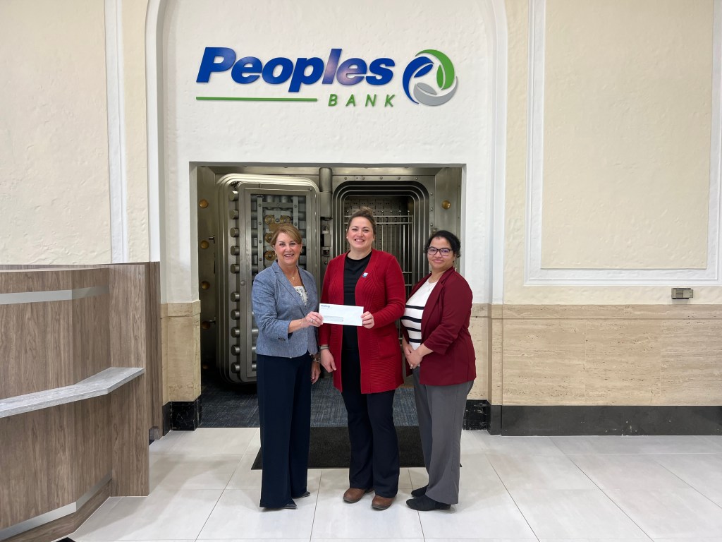 Two Peoples Bank associates stand with a Red Cross representative in front of the Marietta, OH bank vault to present a donation.