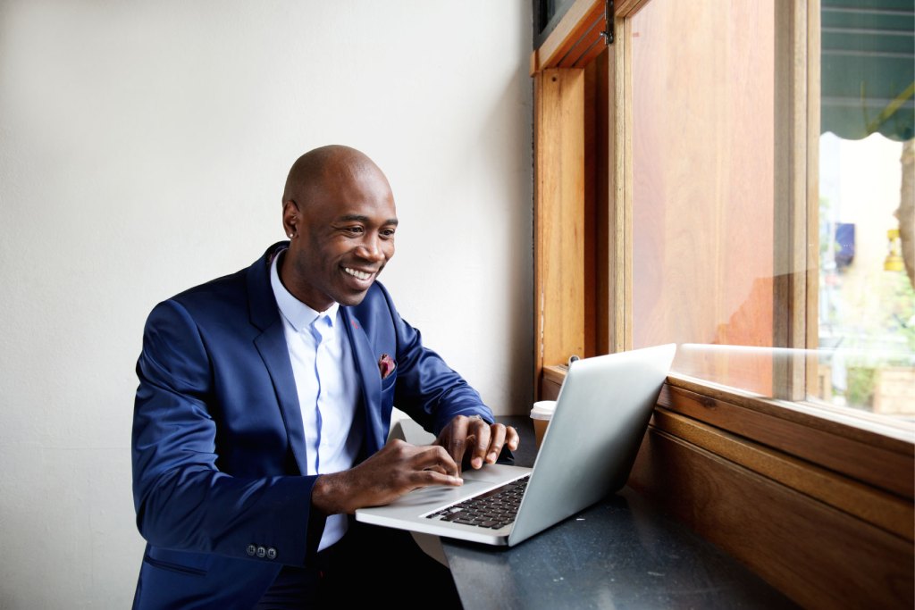 Happy business man working on a laptop in a cafe.