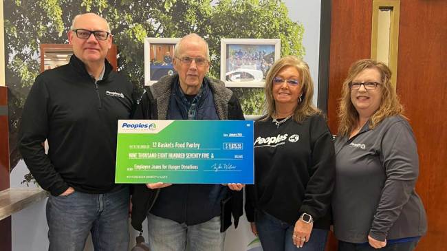 Three Peoples Bank associates present a $9875.55 donation to a representative from the 12 Baskets Food Pantry at the Peoples Bank in Painstville, Kentucky.