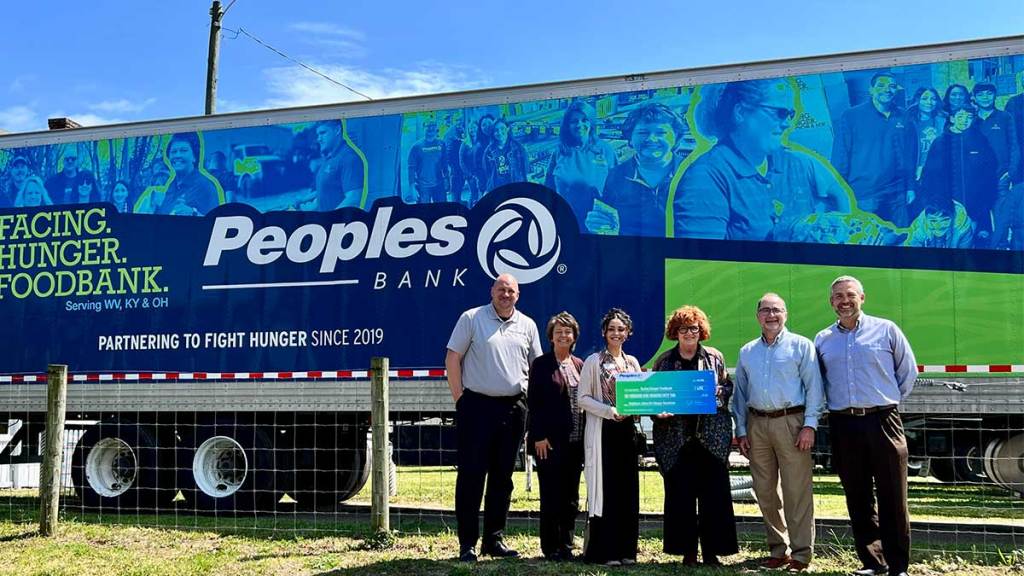Four Peoples Bank associates present a check to two Facing Hunger Foodbank employees while standing in front of the Peoples Bank Facing Hunger Foodbank truck.
