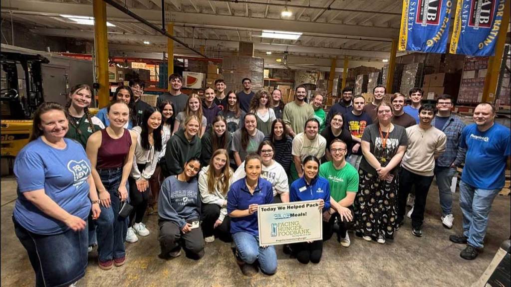 Peoples Bank associates and student volunteers pose in the Facing Hunger Foodbank warehouse after packing 38,033 meals.