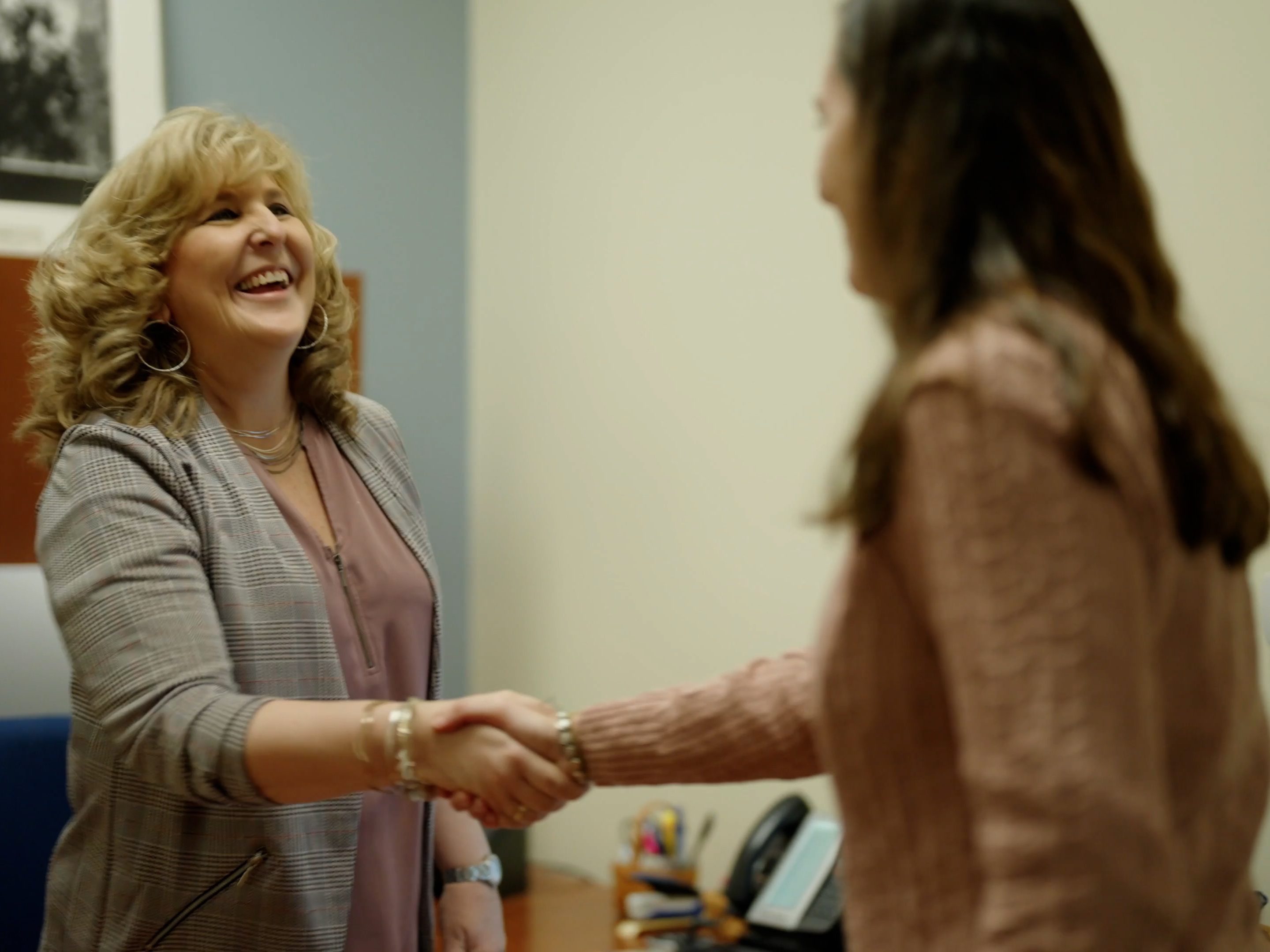 A Peoples Insurance agent (left) shakes hands with a client (right).