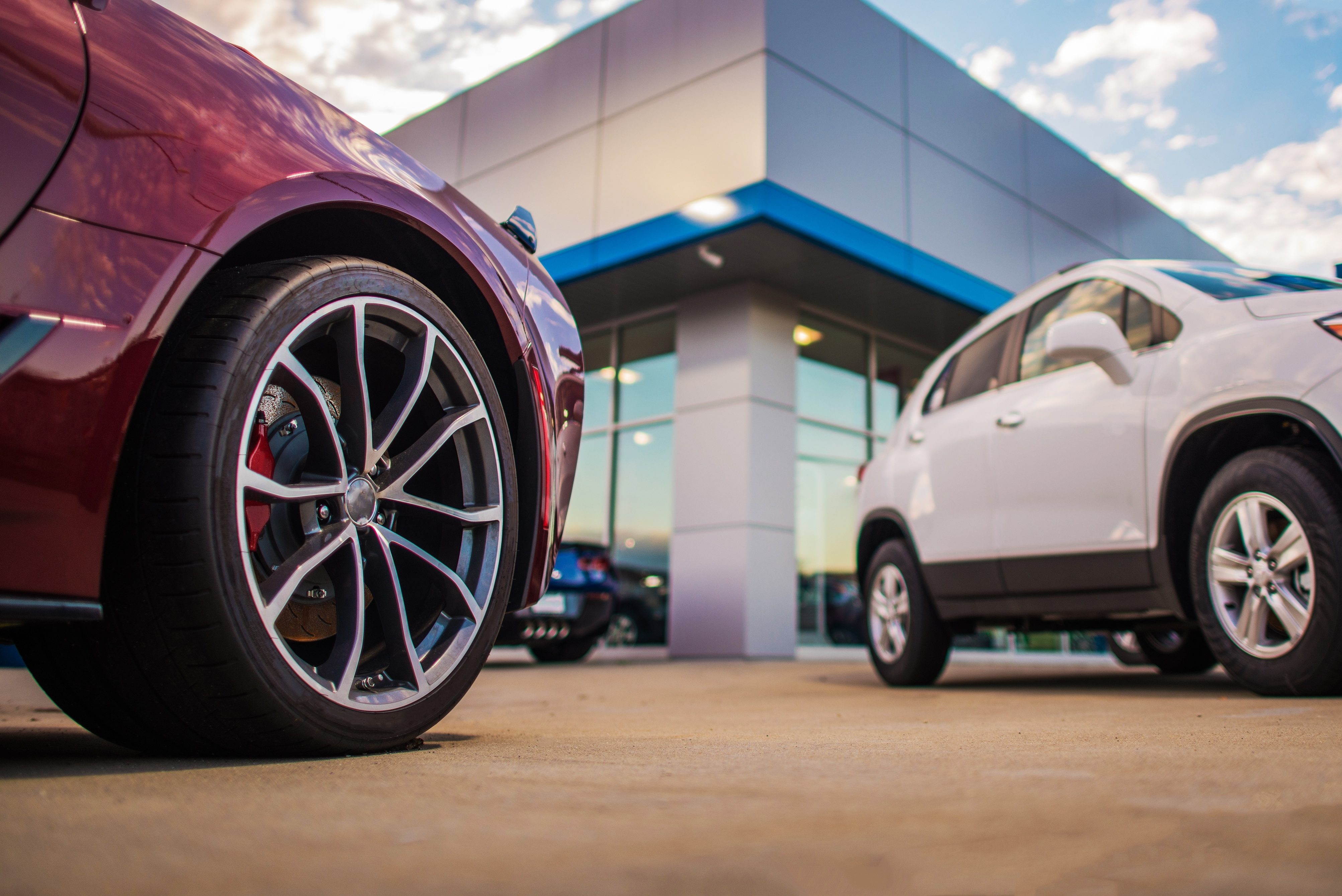 Automotive Dealership Store. New and Pre Owned Vehicles in Front of the Showroom Building.