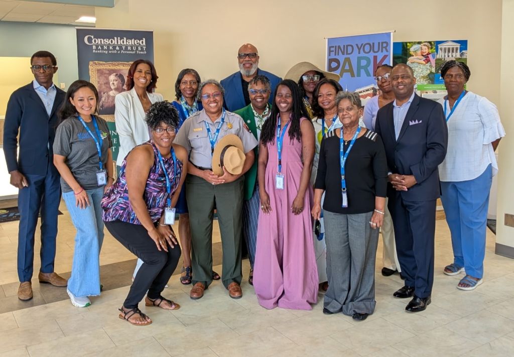 Fifteen attendees, leaders and volunteers from the Maggie Walker Womens Symposium pose for a photo in the Peoples Bank Richmond, Virginia, office.