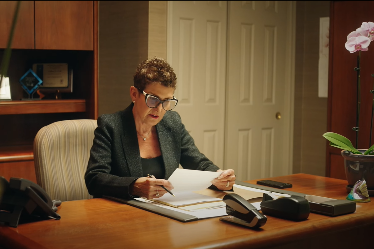 A female attorney sits at a wooden desk looking at case papers.