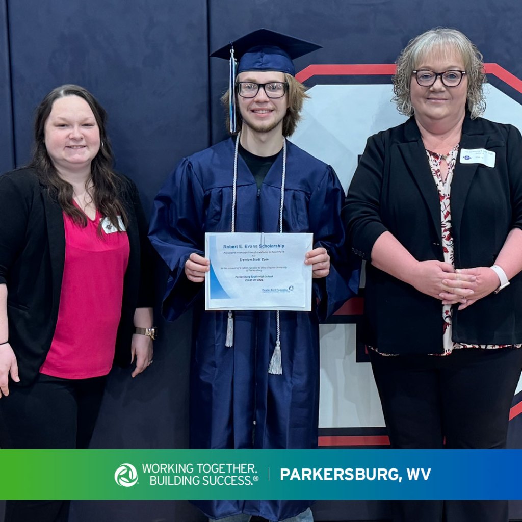 Two Peoples Bank associates stand with a Parkersburg, West Virginia, high school student in a gymnasium to present the Robert Evans Scholarship.