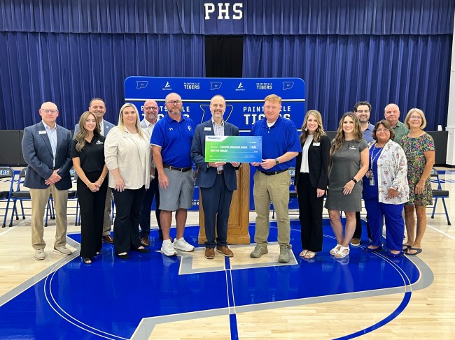 Thirteen Peoples Bank and Paintsville Independent School staff members pose for a check presentation photo.