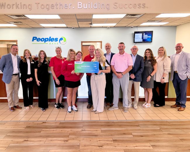 Thirteen Peoples Bank associates and representatives from the Paintsville Apple Festival gather for a check presentation photo.