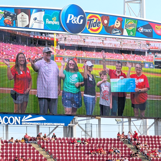 Seven Peoples Bank associates stand on the field at the Great American Ball Park to present a donation to the Home Emergency Program.